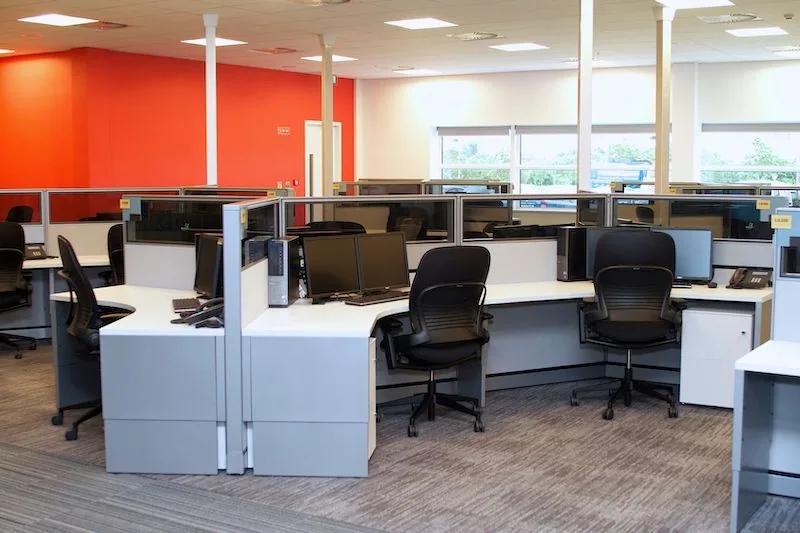 Open-plan office with gray cubicles and black chairs
