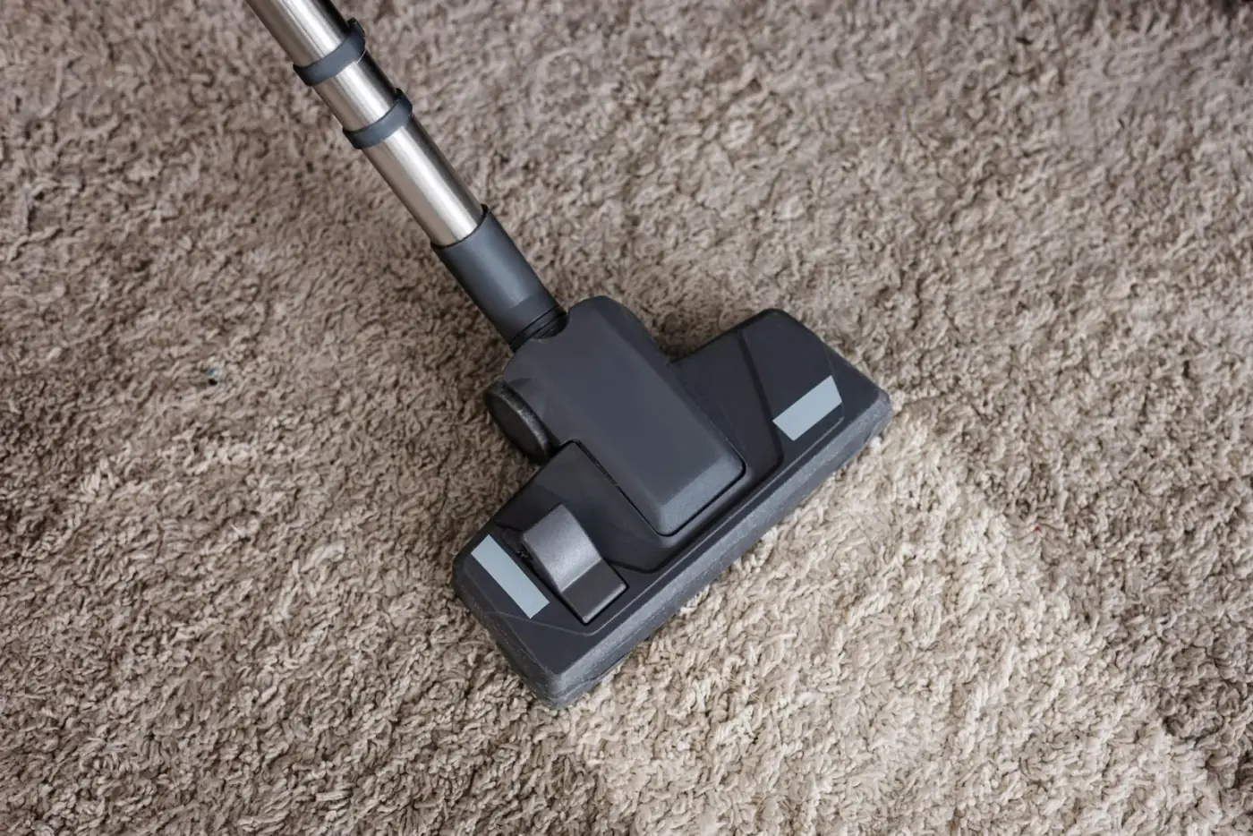 Vacuum cleaner head on beige carpet, cleaning.