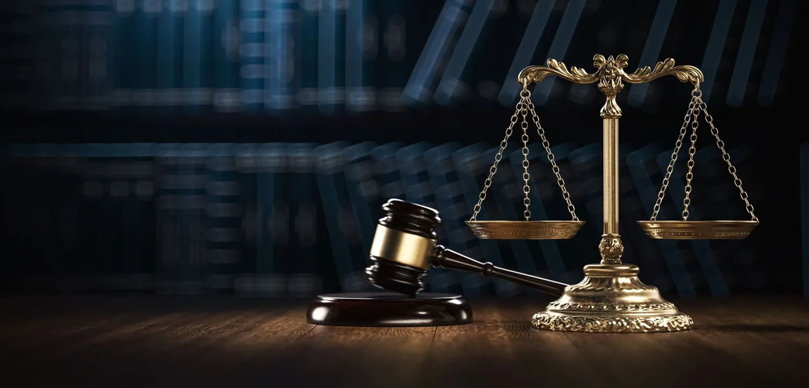 Gavel and scales of justice on a wooden surface with a dark blurred background.